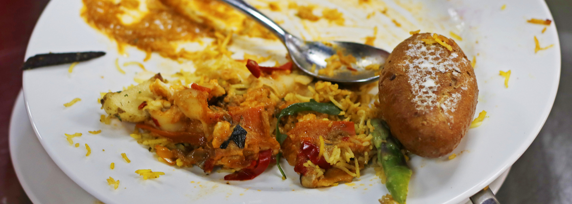 A stack of dirty plates with uneaten food in a restaurant kitchen